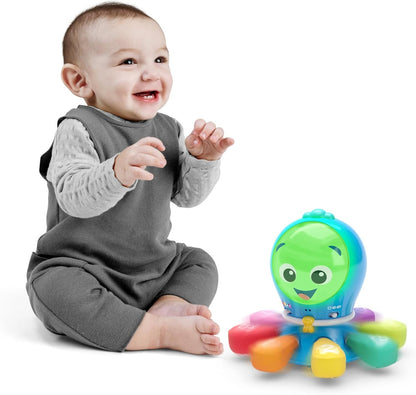 Siedzące dziecko obok ośmiornicy Baby Einstein Ocean Explorers z zieloną twarzą widoczną na zdjęciu.